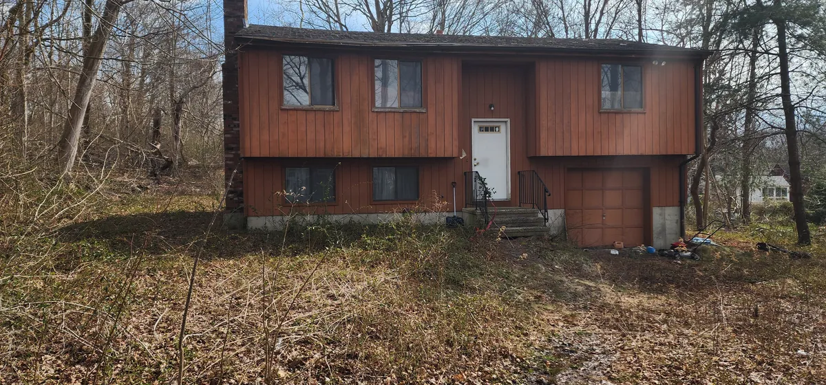A split-level house on an overgrown lot on Partridge Lane in Clinton, as it stood when Next Door Properties walked it