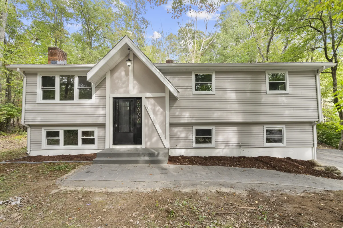 A grey raised ranch among trees in Willington, bought by Next Door Properties