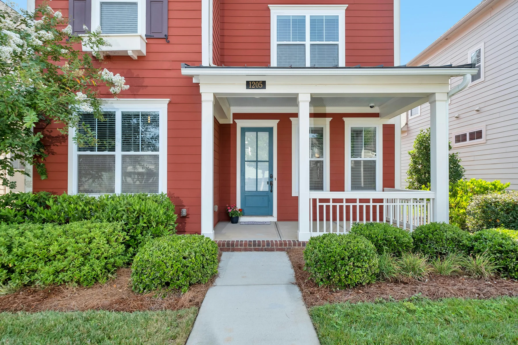 The porch and blue front door of a red-painted timber house